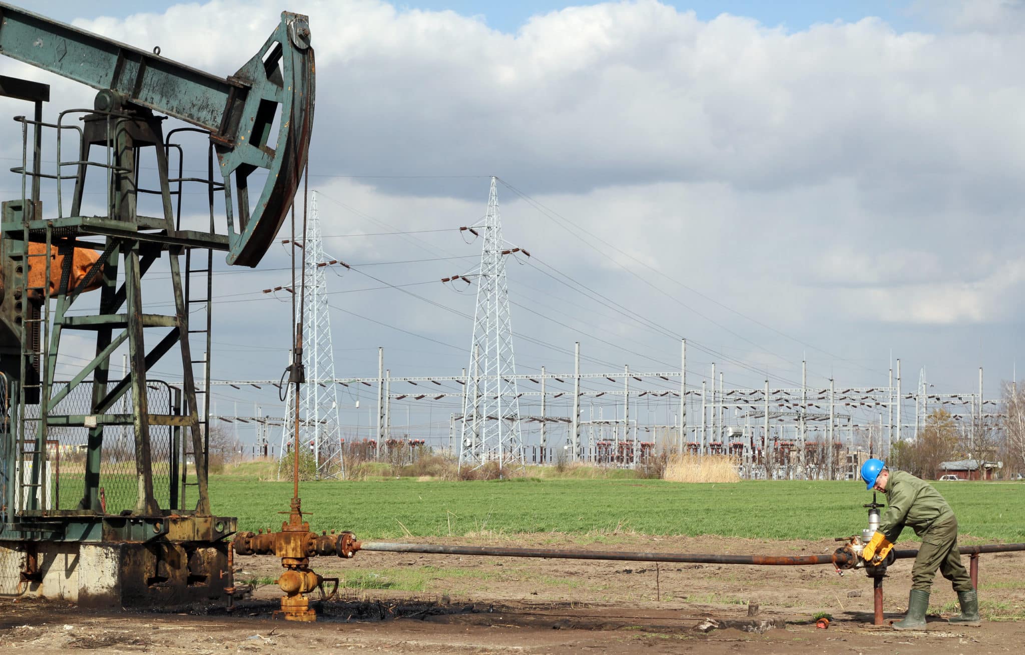 oil field with pump jack and worker