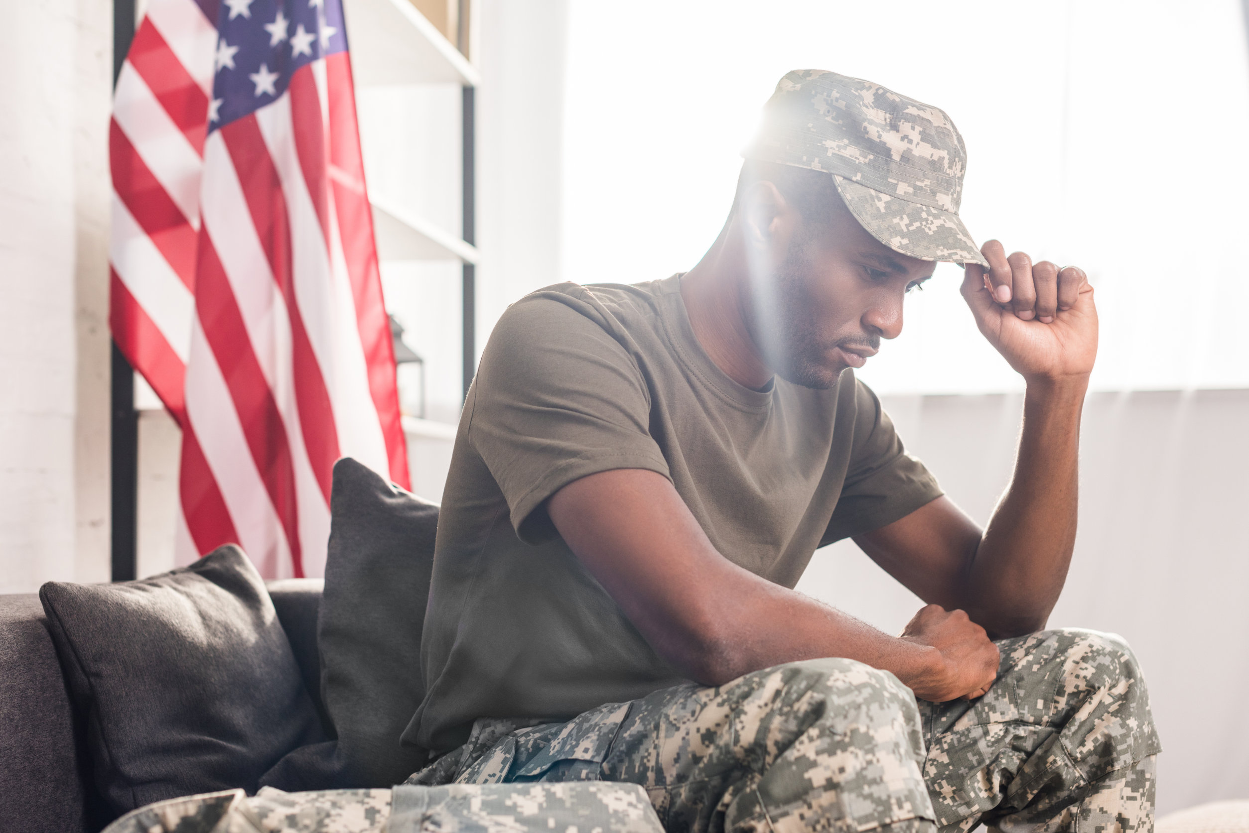 African american soldier in camouflage clothes sitting on sofa